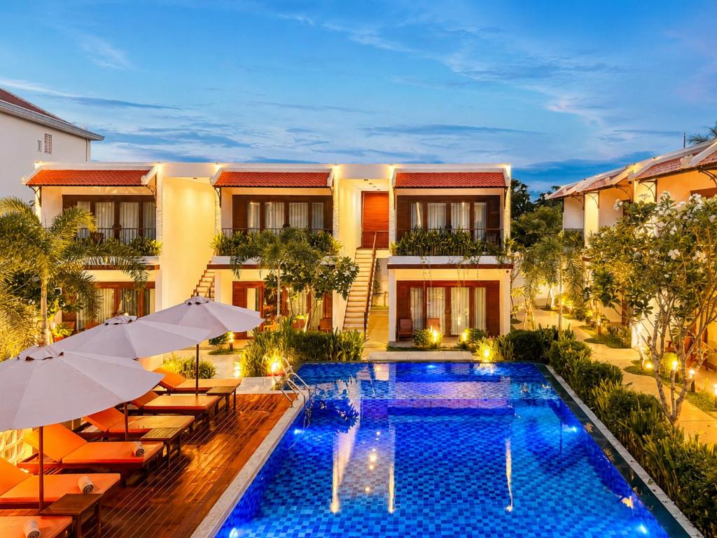 a hotel with a swimming pool with chairs and umbrellas at Happy Resort Siem Reap in Phumi Ta Phul