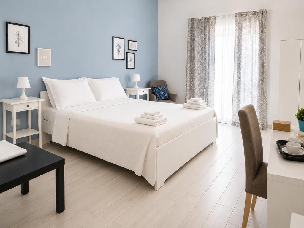 a white bedroom with a white bed and a table at Torrearsa 17 in Trapani