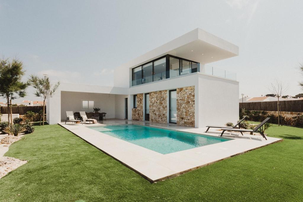 a villa with a swimming pool in front of a house at Canalola in Cala en Bosc