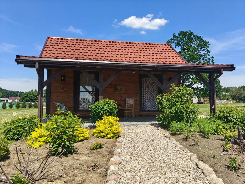 a wooden cabin with a red roof in a garden at Słoneczne Łąki in Wólka Soseńska