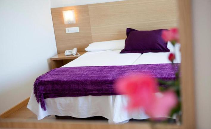 a hotel room with a bed with a purple blanket at Hotel Brisa del Mar in O Grove