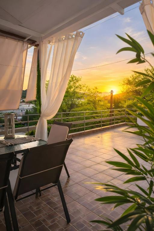 a patio with a table and chairs and the sunset at Domenica apartment in Salamina