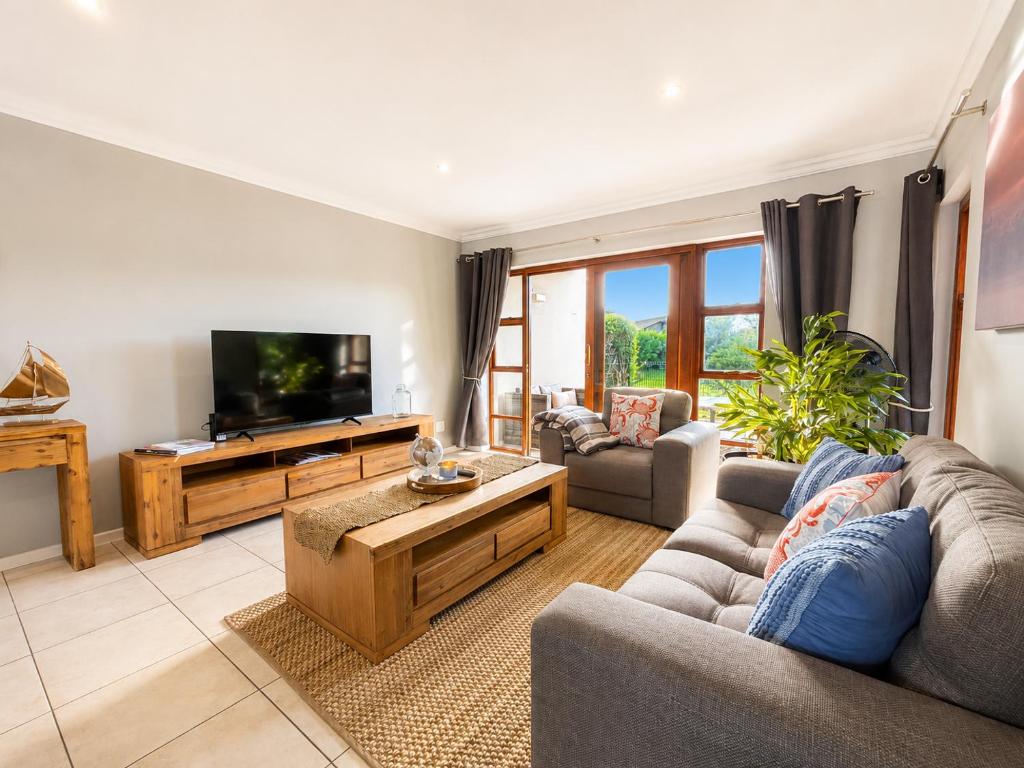 a living room with two couches and a flat screen tv at Captains Quarters in Plettenberg Bay