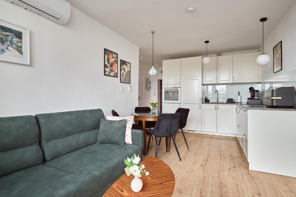 a living room with a green couch and a kitchen at Apartament Teatralny - Komfort w Sercu Miasta Klimatyzacja in Opole