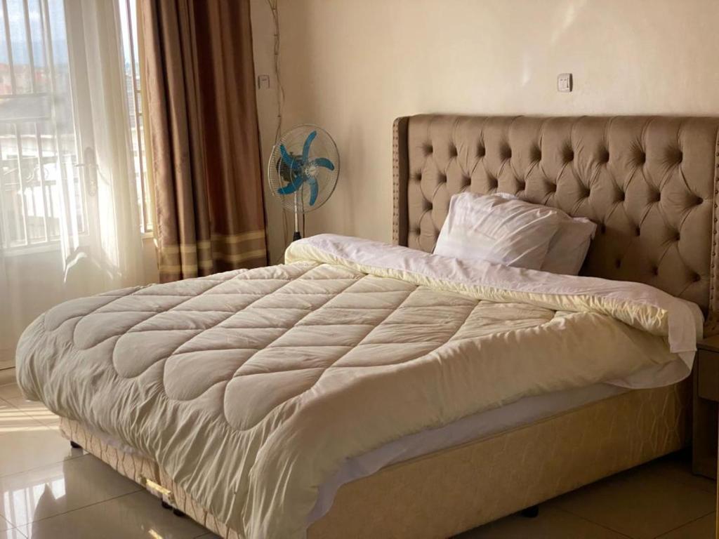 a bedroom with a large white bed with a large window at KIGALI FANTASTIC Aparthotel in Kigali