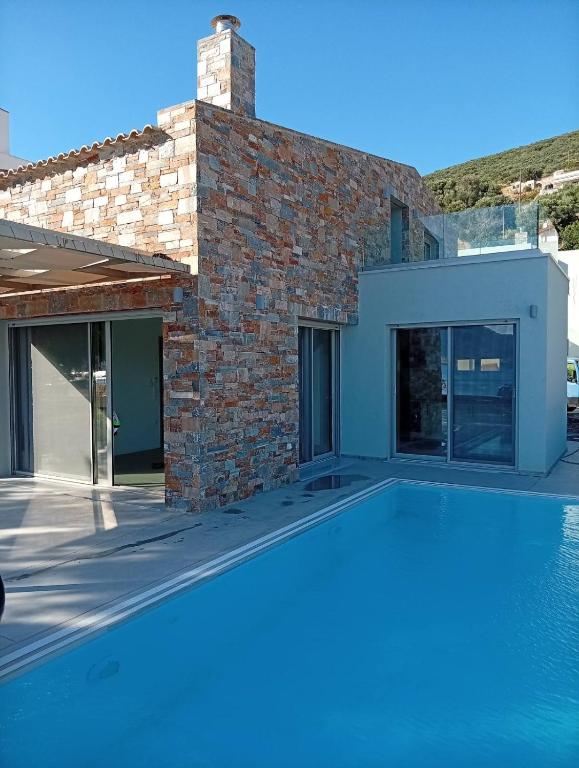 a swimming pool in front of a brick house at Almira Seaside Suites in Áyios Dhimítrios