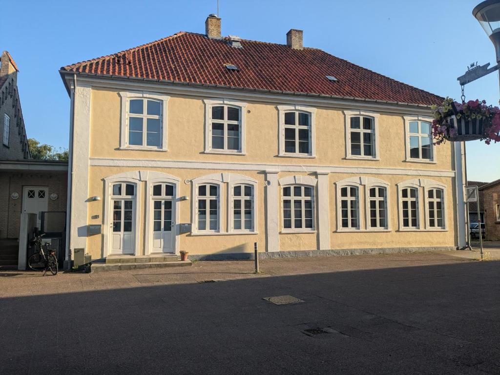 a large yellow house with a red roof at Stubbekøbing Square View Stopover in Stubbekøbing