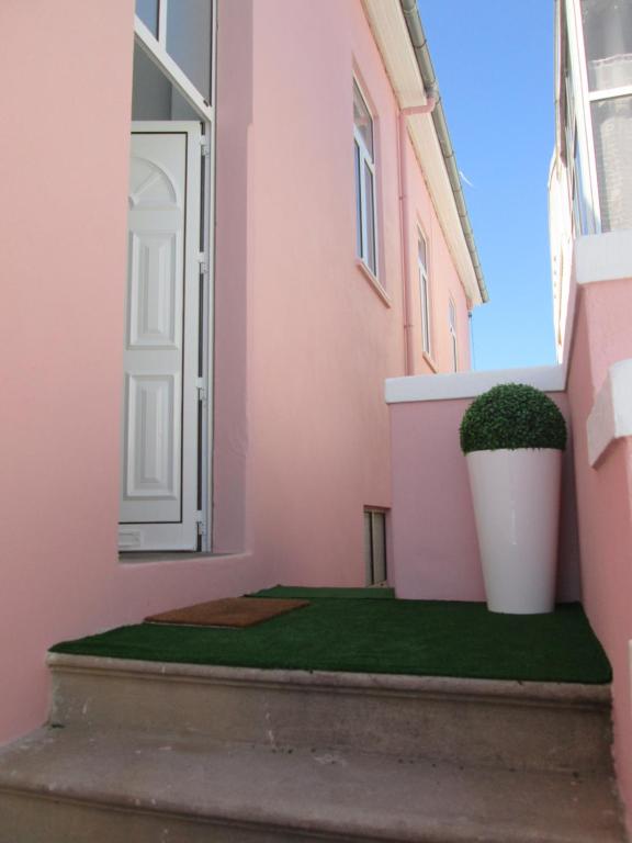 ein rosafarbenes Gebäude mit einer Pflanze in einem Topf in der Unterkunft Why Not? Guest House Espinho in Espinho