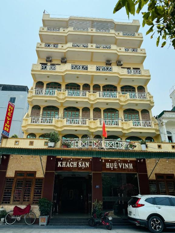 a large yellow building with balconies on a street at Huệ Vinh Hotel in Cửa Lô