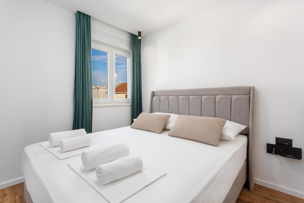 a white bedroom with a large bed with two pillows at Apartmani Ivano & Anđelo in Međugorje
