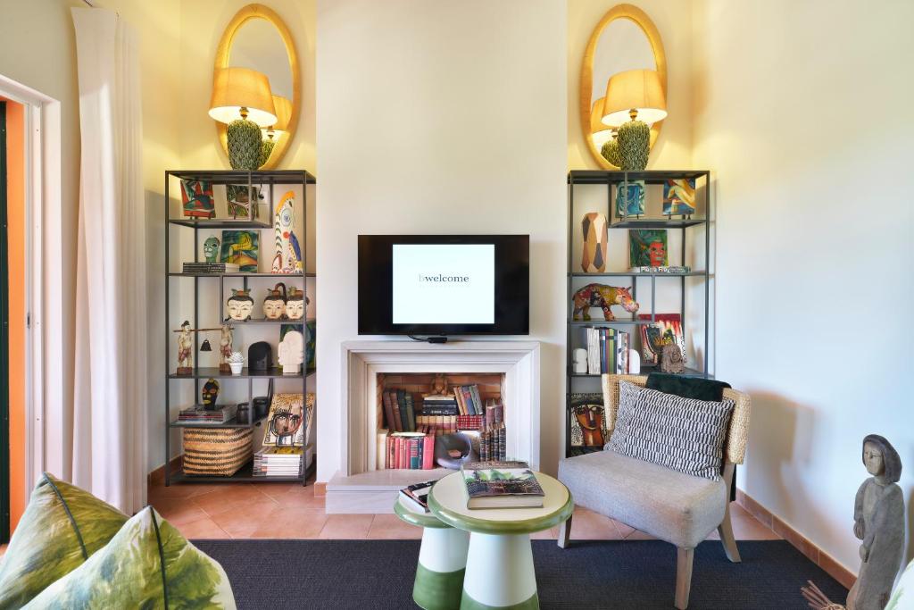 a living room with a tv and a chair and a fireplace at bwelcome aroeira beach & golf in Charneca