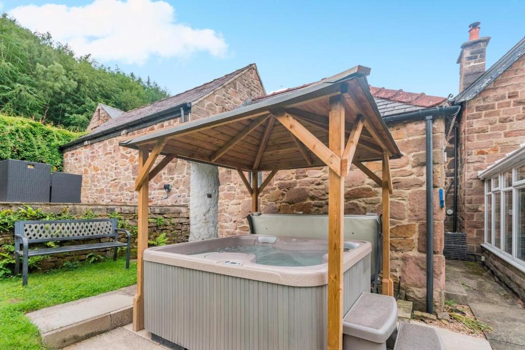 a hot tub with an umbrella in a yard at 4 Bed in Matlock oc-52094 in Highpeak Junction