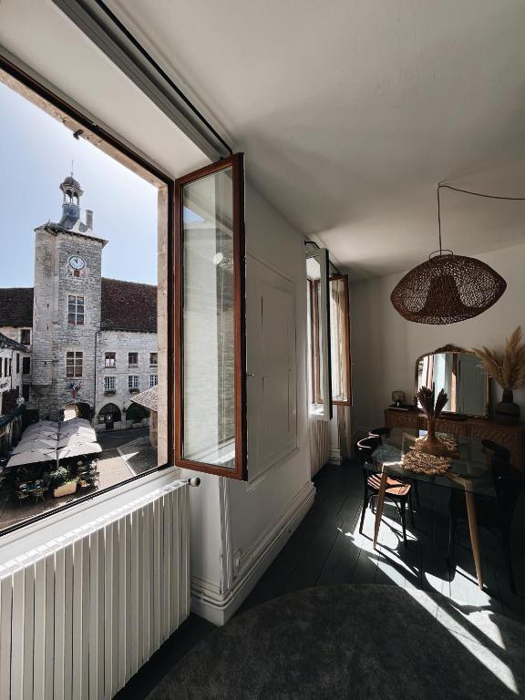 a room with a window and a table and a clock tower at Le Haut des Halles in Martel
