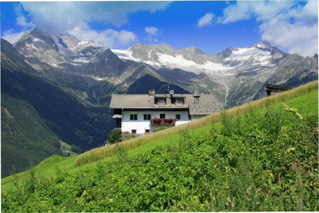 a house on a hill with mountains in the background at Schauinstal Appartement 2 in Lutago