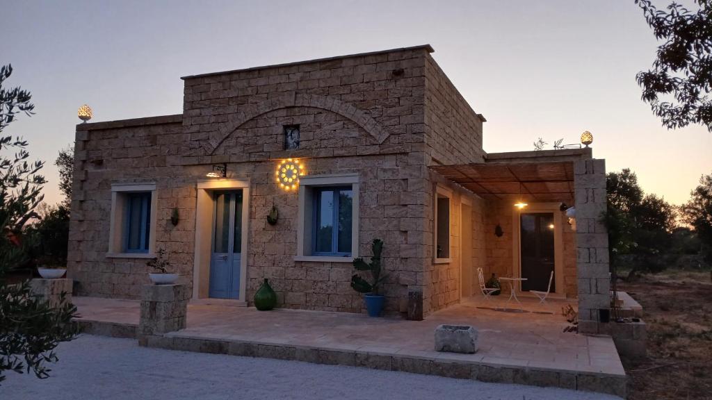 a small brick house with a sunset in the background at Casale Mute Terre in Tuglie