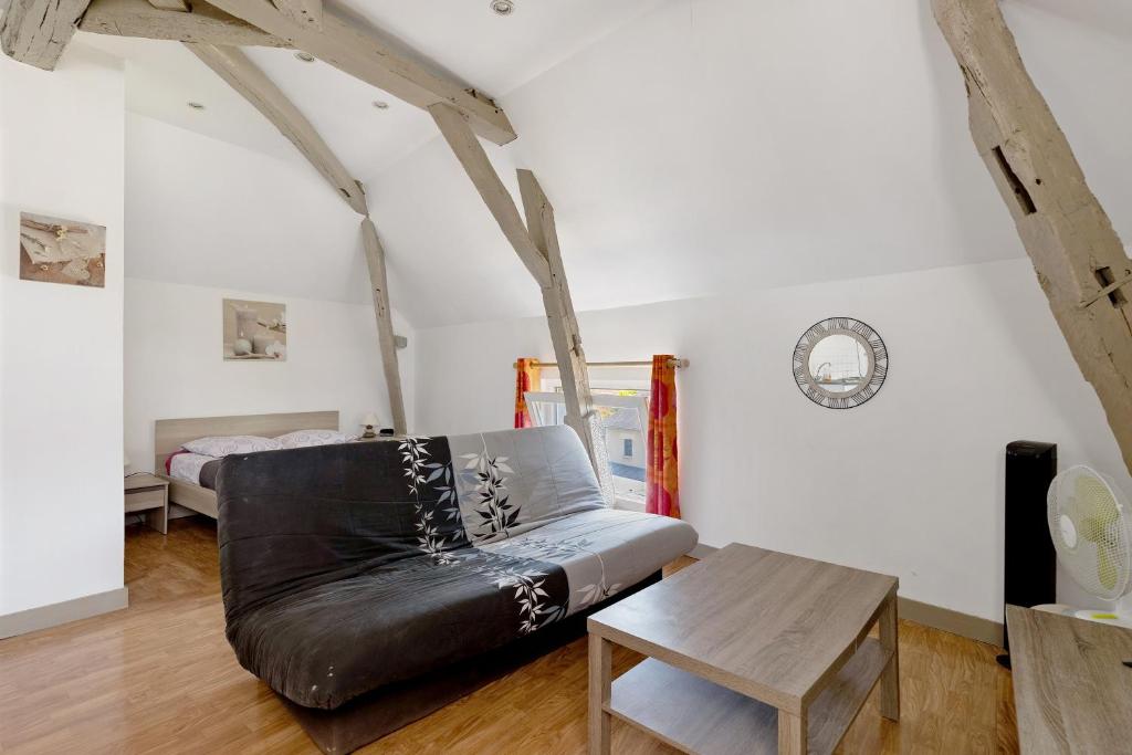 a living room with a black leather couch and a table at Studio 7 3 Min Du Futuroscope in Chasseneuil-du-Poitou