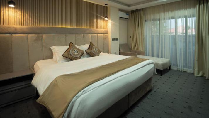 a hotel room with a large white bed with pillows at Vynedresa Hotel, Abuja in Abuja