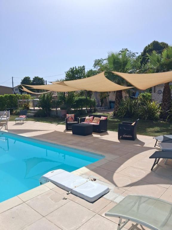 a pool with chairs and umbrellas next to at Gite du Passignac in Saint-Maigrin