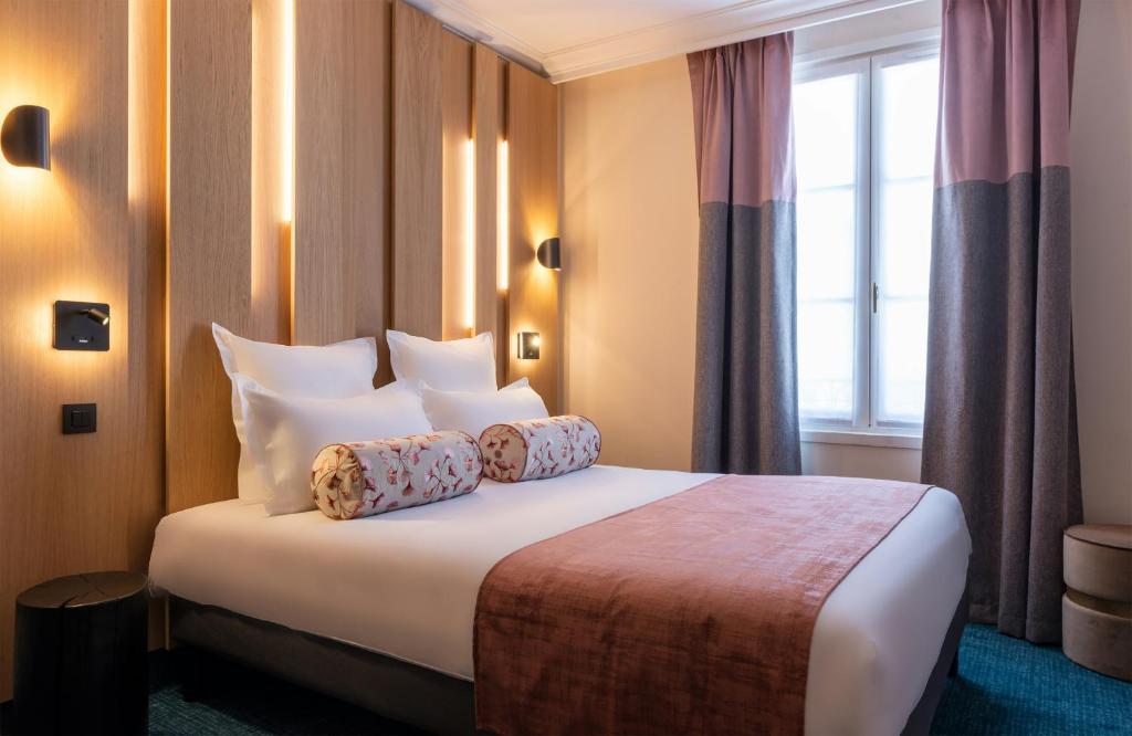 ein Hotelzimmer mit einem Bett mit Kissen und einem Fenster in der Unterkunft Leonardo Boutique Hotel Paris Opera in Paris
