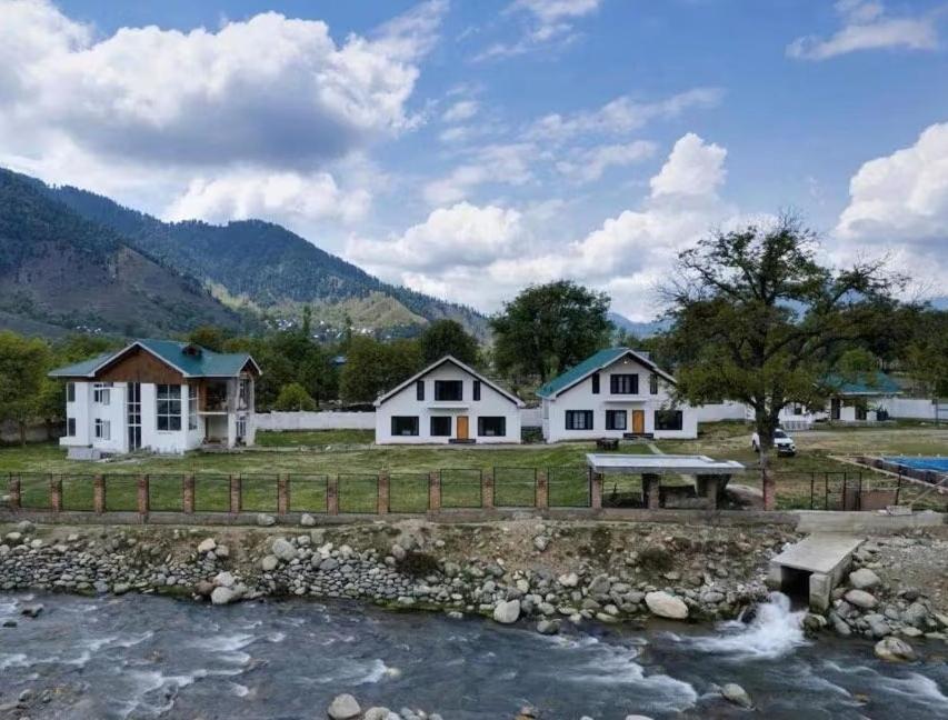 a group of houses next to a river at kanwal cottages safa resort in Dandpur