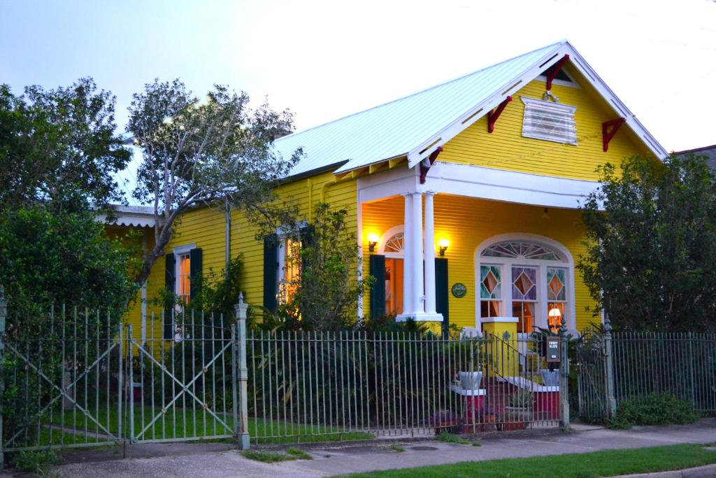 a yellow house with a fence in front of it at Auld Sweet Olive Bed and Breakfast in New Orleans