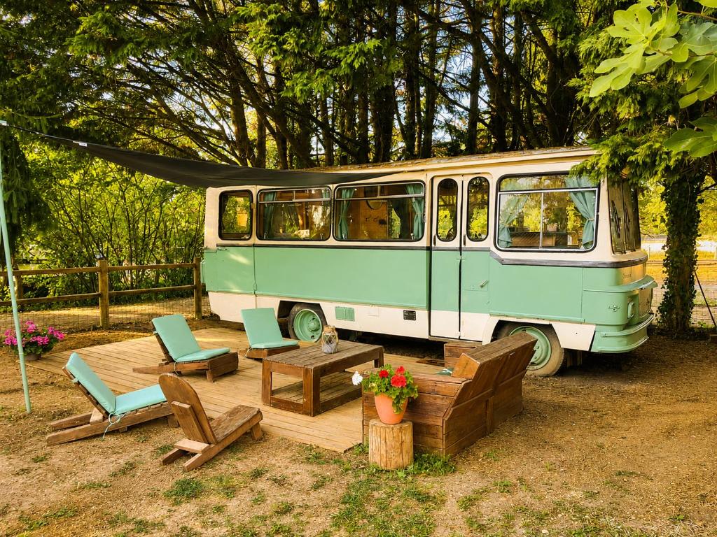 a green van parked next to a table and chairs at Tiny house - Bus insolite - avec Escape Game in Mignaloux-Beauvoir