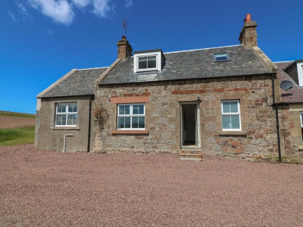 an old stone house on a gravel driveway at Keepers Cottage in Haddington