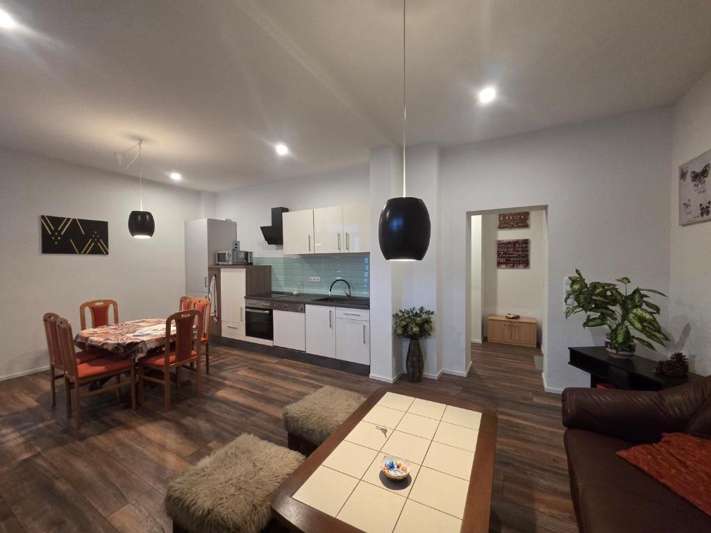 a living room with a table and a kitchen at Apartment am Saaleradwanderweg in Merseburg