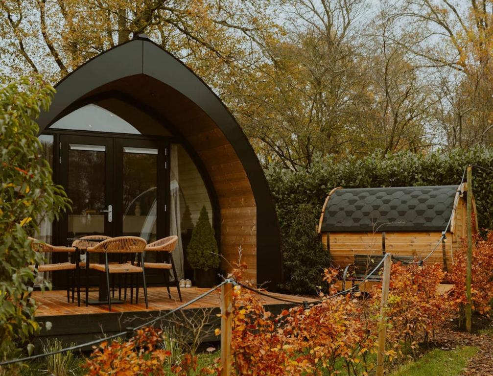 a cabin in a garden with a table and chairs at luxury cottage with sauna in Milsbeek