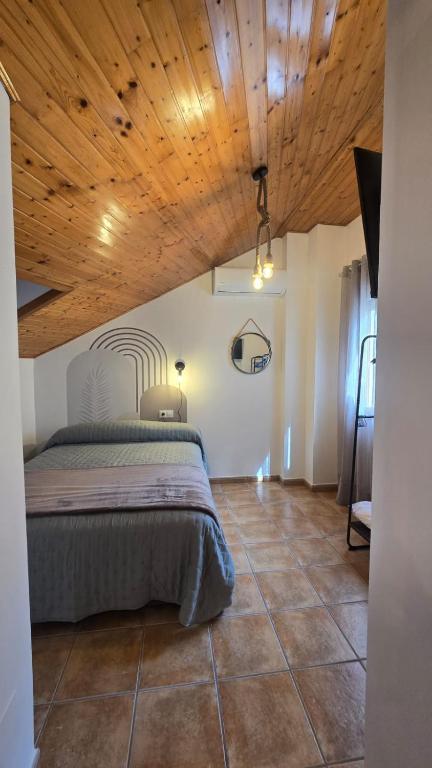 a bedroom with a bed and a wooden ceiling at La Ribera in Arroyo Frio