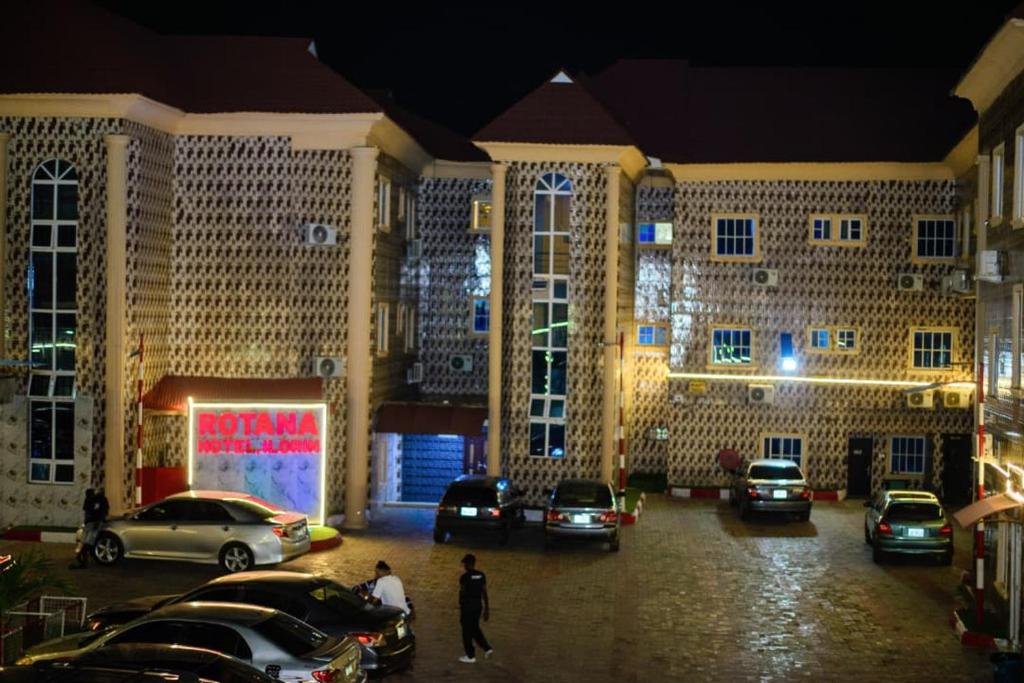 a large building with cars parked in a parking lot at Rotana Hotel and Suits in Ilorin
