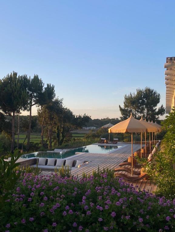 a resort with a pool and umbrellas and flowers at Quinta Amala in Melides
