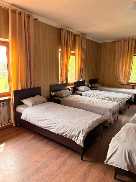 a row of beds in a room with windows at Safari Stop Hostel in Almaty