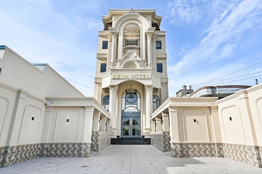 a large white building with a clock tower at Khách sạn Neva in Long An