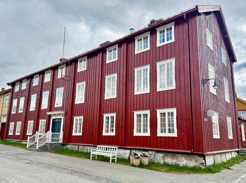 a red building with a bench in front of it at Finnegården Røros in Røros