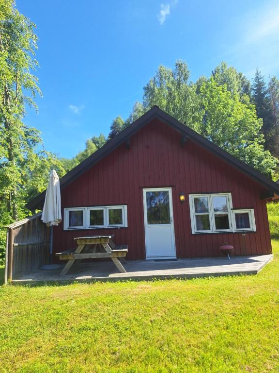 a red barn with a picnic table and an umbrella at Brufoss Hytte og Laksesenter in Svarstad