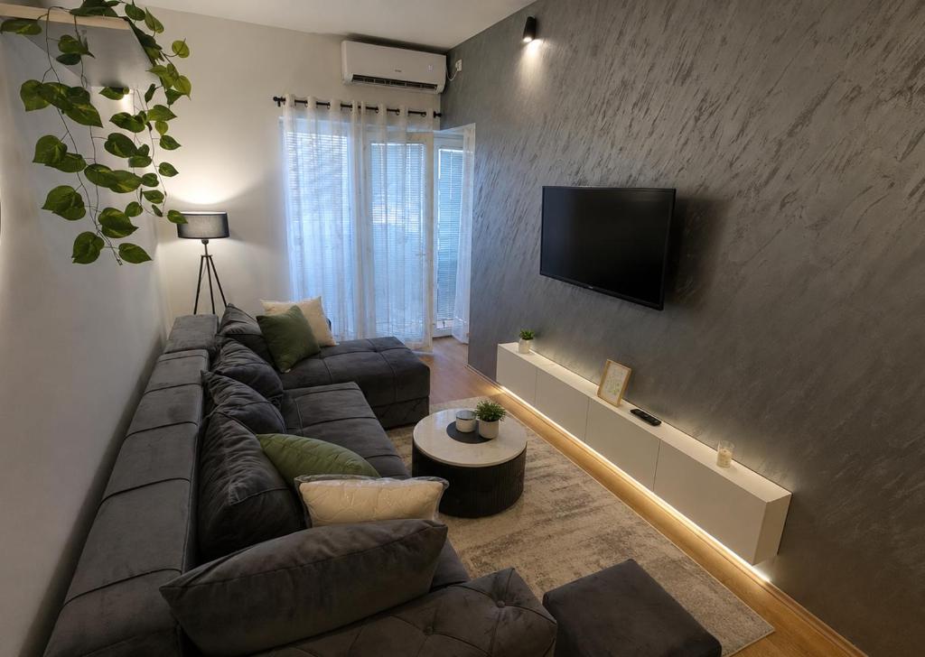 a living room with a couch and a tv on a wall at Urban Center Paraćin in Paraćin
