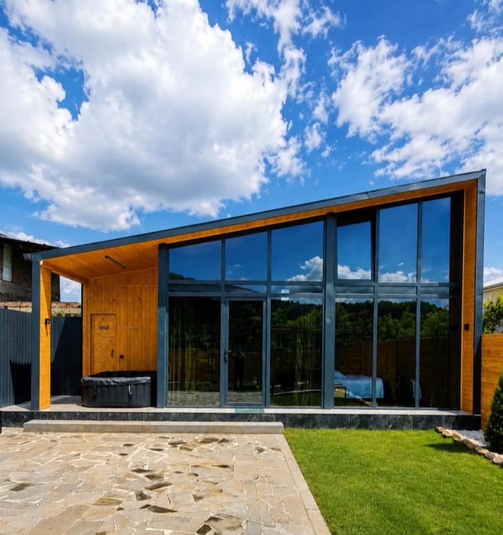 ein Haus mit großen Glasfenstern und einem Rasen in der Unterkunft Lori INN in Stepanawan