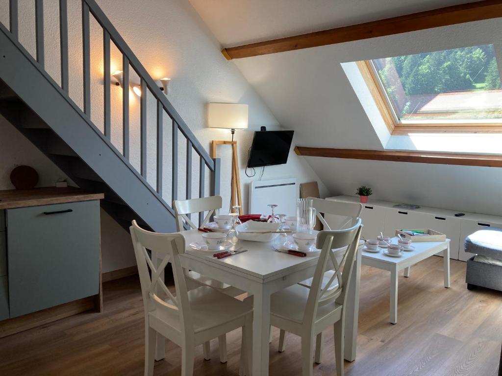 a dining room with a white table and chairs at 2 chambres avec mezzanine in Le Lioran