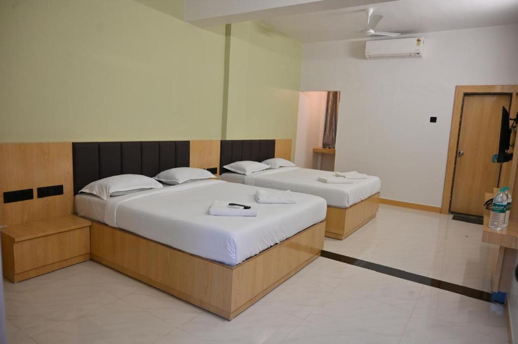 two beds in a room with twoermott at Hotel Sai Vaibhav in Shirdi