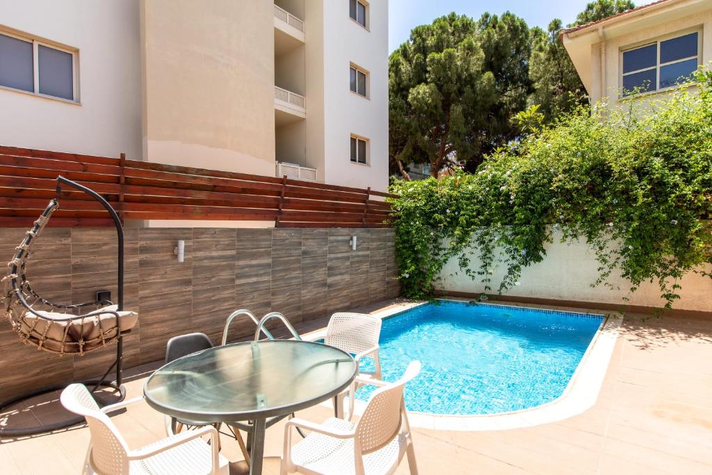 a patio with a glass table and chairs next to a swimming pool at Gaia - 4 Bedroom House in Larnaca in Larnaca