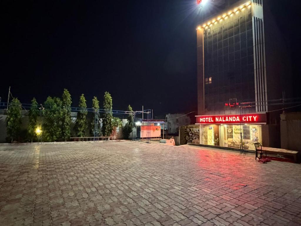 an empty parking lot in front of a building at night at Hotel Nalanda City in Nalanda