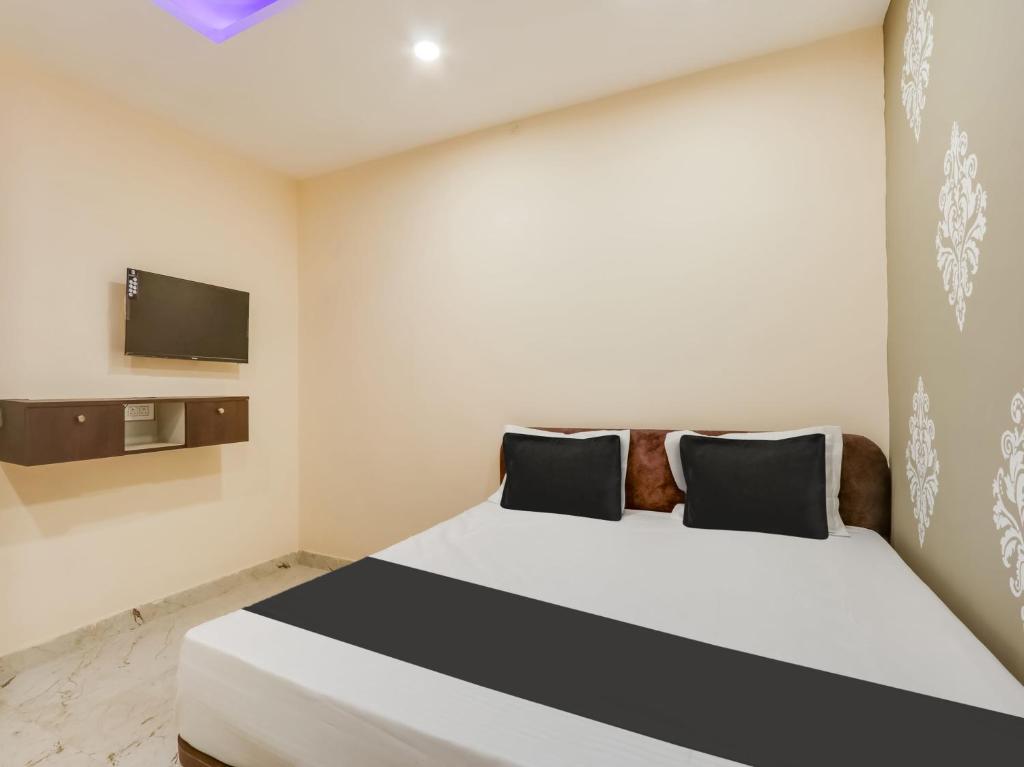 a bedroom with a bed and a tv on the wall at Hotel O BSS INNS in Warangal