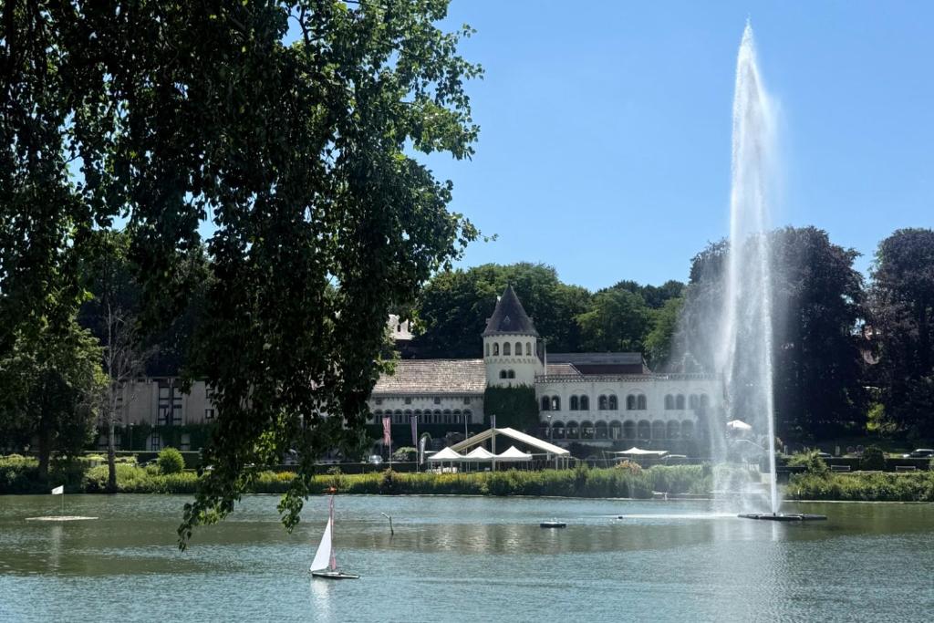 a sailboat in the water in front of a building at Martin's Château Du Lac in Genval