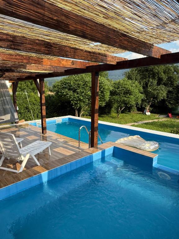 a swimming pool with a wooden pergola and a swimming poolvisor at Kuća za odmor Nera in Hadžići