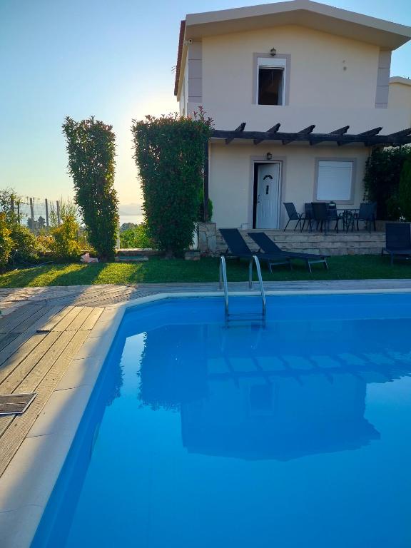 a swimming pool in front of a house at Serenity Horizon Villa in Theologos