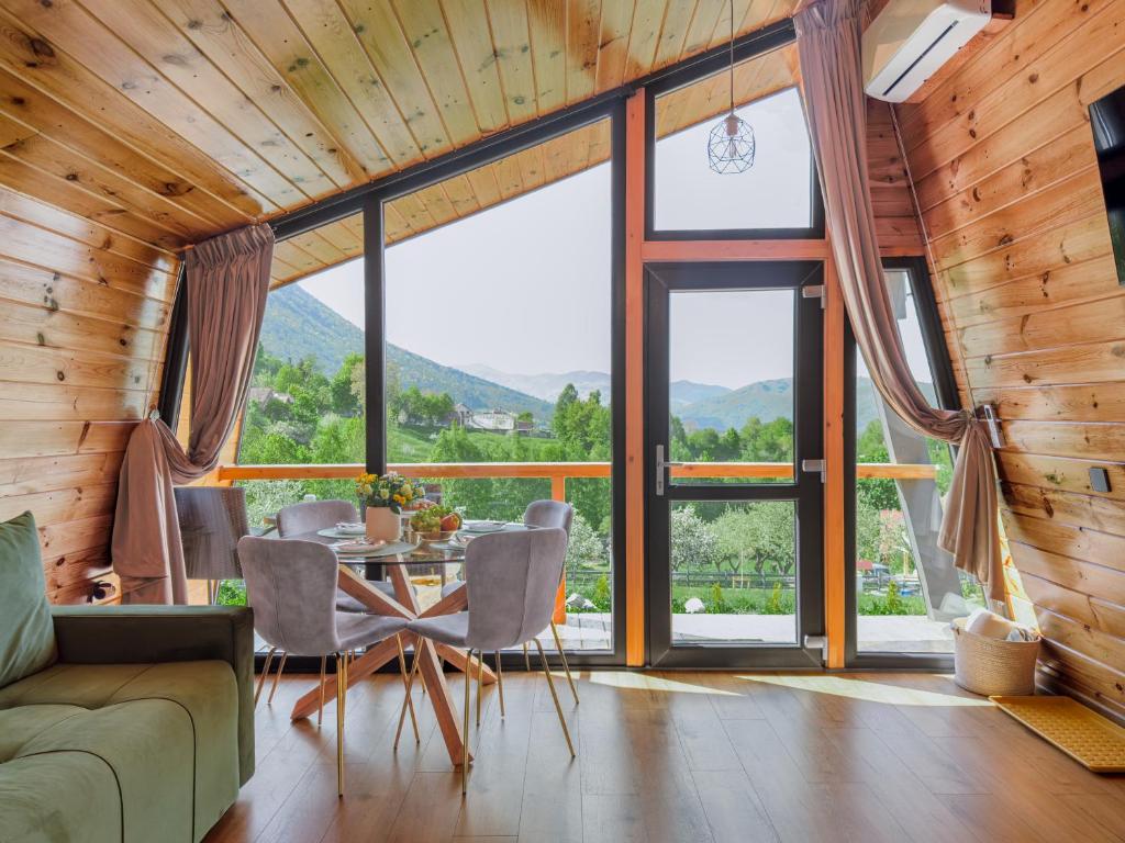 a living room with a table and chairs and large windows at Forest Cuib in Predeluţ
