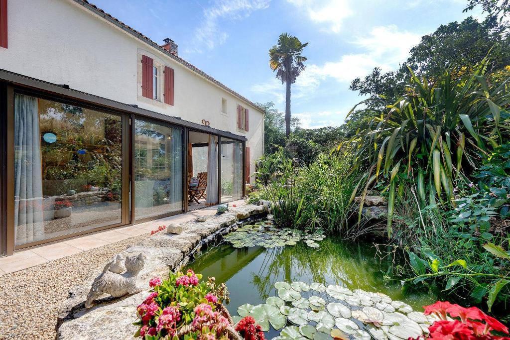 a house with a koi pond in a garden at Chambres D'hôtes Le Peux in Saint-Pierre-le-Vieux
