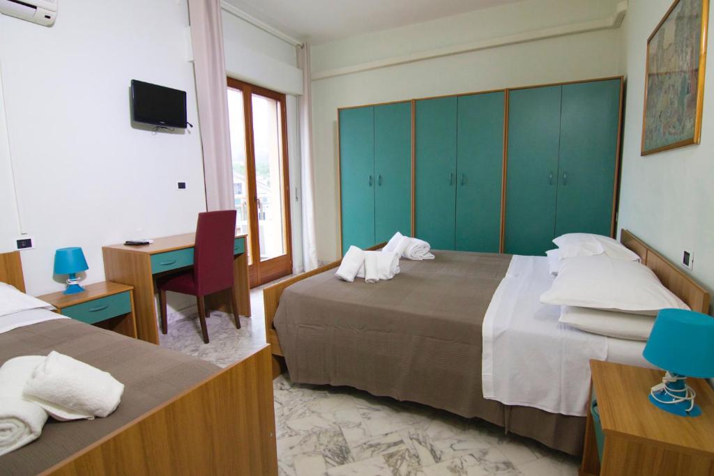 a hotel room with two beds and a desk and a computer at Hotel Roma in Pineto