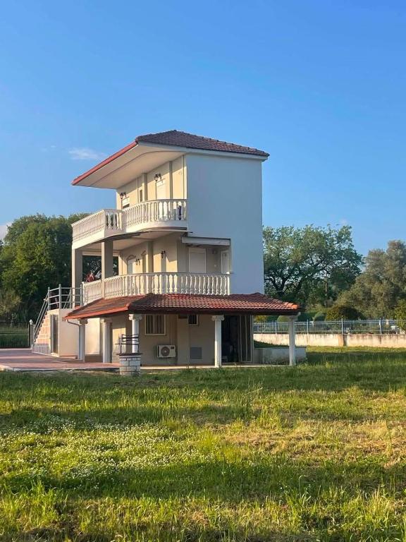 a large house with a balcony and a grass field at Olive Tree Villa in Preveza